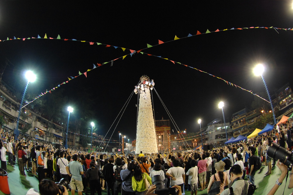 Brave competitors scramble up an enormous bamboo tower studded with imitation buns