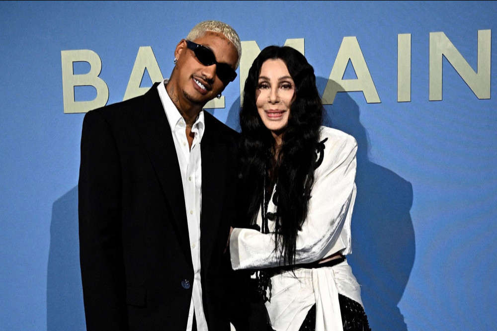 Cher has confirmed she is back with her toyboy lover Alexander ‘AE’ Edwards by cosying up to him at the Balmain fashion show in Paris