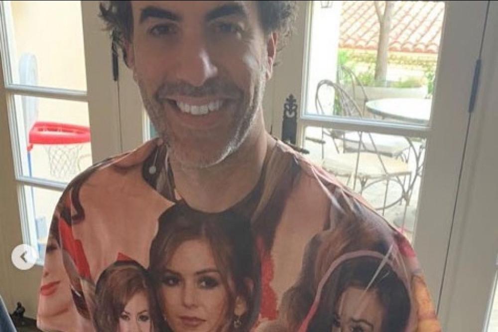 Sacha Baron-Cohen posing in his unique T-shirt to celebrate 20 years with Isla Fisher
