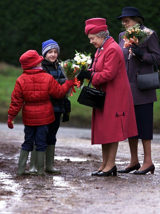 Queen Elizabeth II accepts flowers at St Peter St Paul's Church in Norfolk, 2001, dodging muddy puddles as she does so! / Picture Credit: PA Images/Alamy Stock Photo