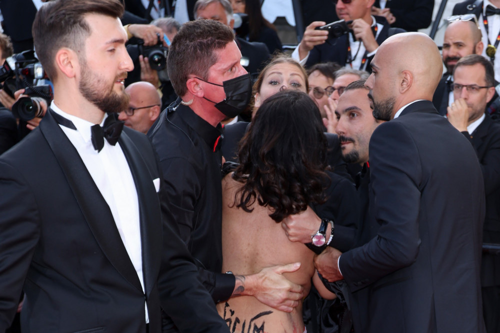 A nude woman is dragged away from the red carpet at Cannes Film Festival after staging a protest