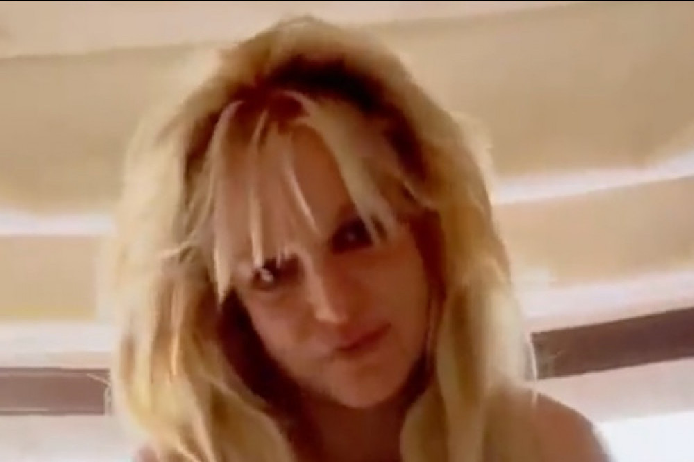 Britney Spears marked first new single in six years topping the iTunes charts in 40 countries by exclaiming ‘HOLY S***!’ on Twitter and posing apparently naked in a bathroom during an online video