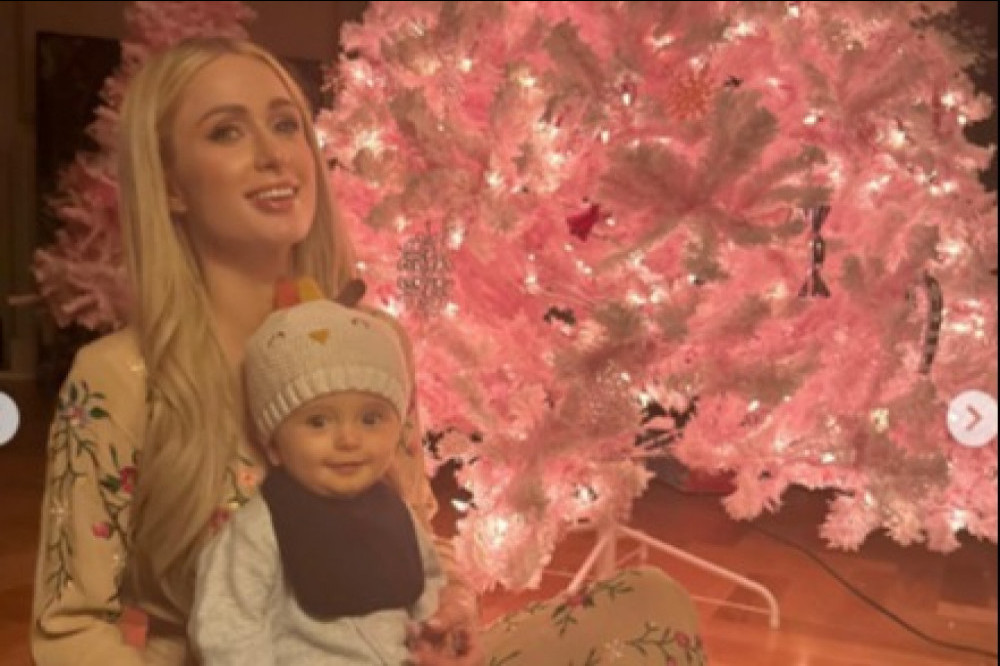 Paris Hilton and her son Phoenix pose in front of a pink Christmas tree