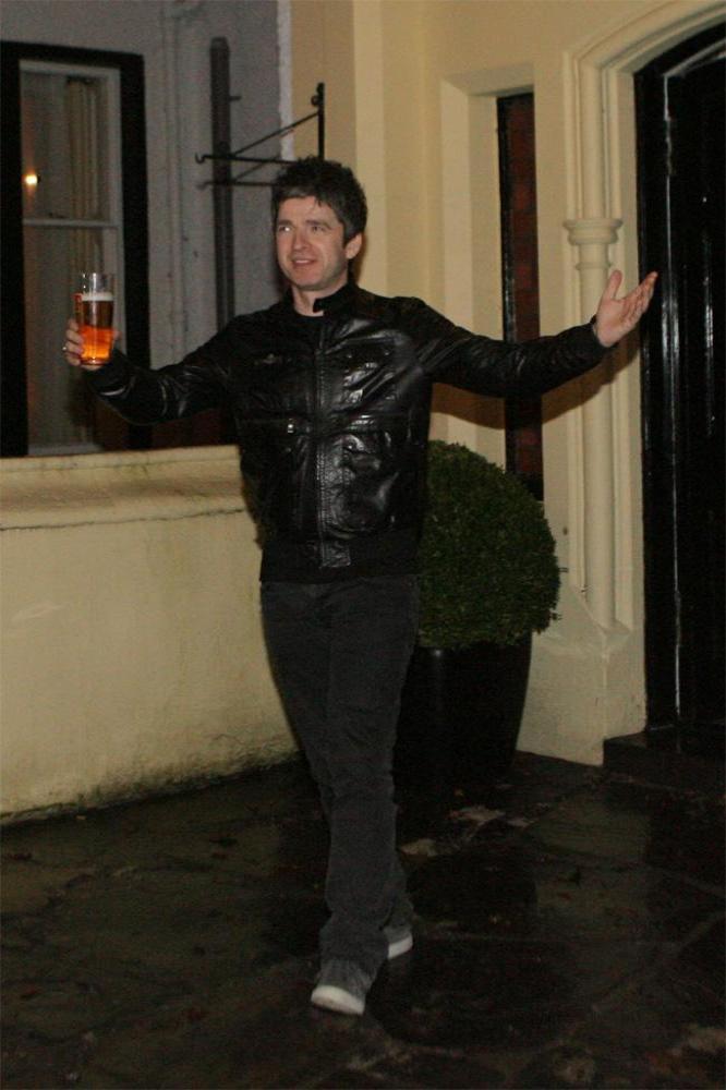 Noel Gallagher holding a pint of Tennent's Lager while standing outside the Craigellachie Hotel in the Scottish Highlands 
