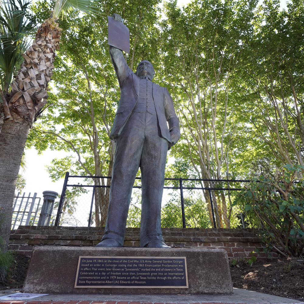 A statue depicts a man holding the state law that made Juneteenth a state holiday in Galveston, Texas.